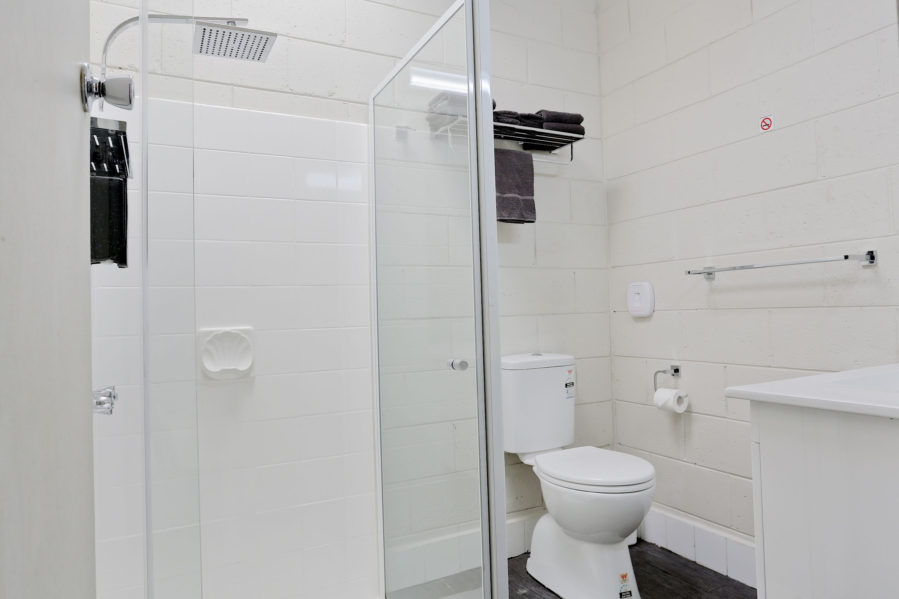 A modern bathroom with a glass-enclosed shower, a toilet, and a sink.