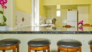 A kitchen with a marble countertop, wooden stools, and a potted orchid. - Lee Farm Stay Cottages (Booie)