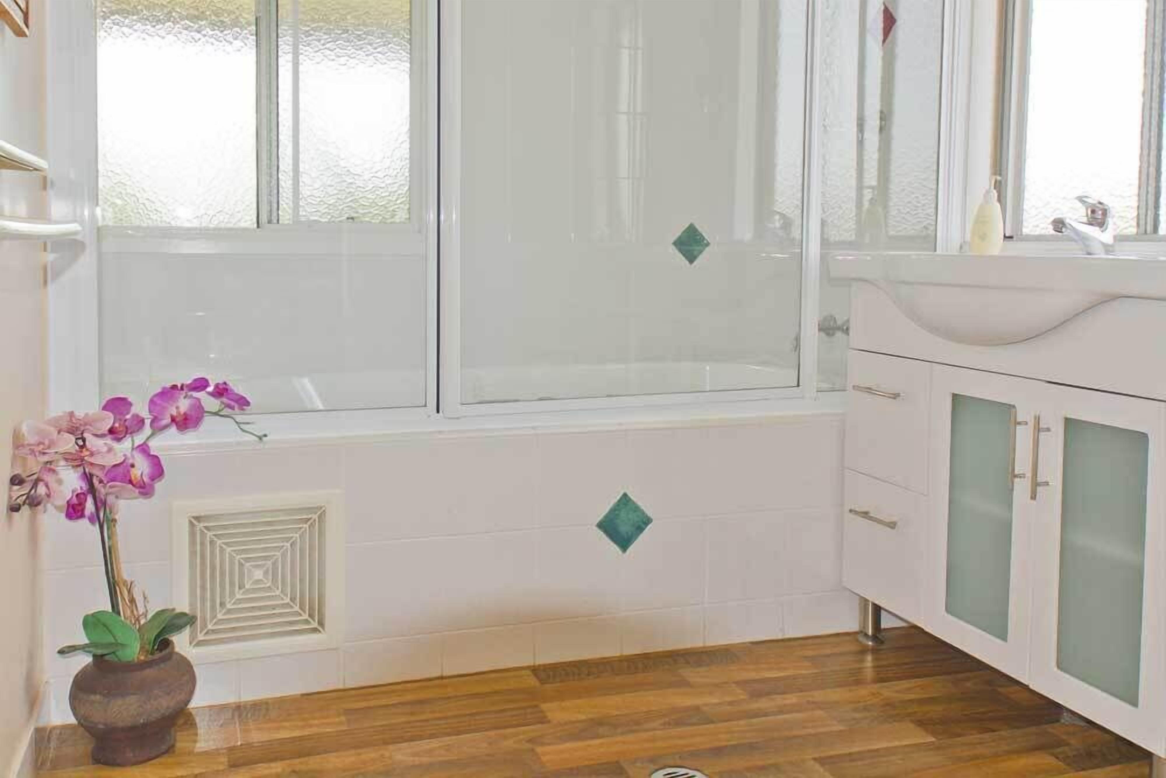 Een badkamer met een bad, een wastafel en kastjes.