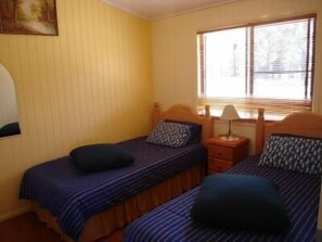 A room with two beds, each with a pillow and a bedside table with a lamp. - Lee Farm Stay Cottages (Booie)