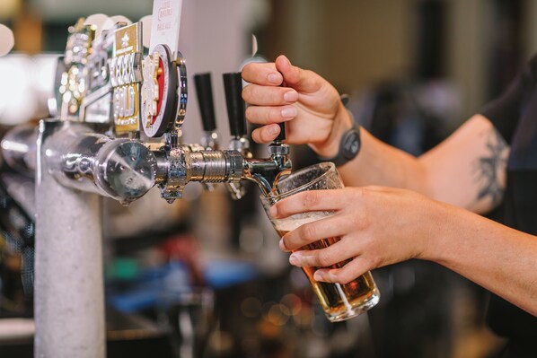A person pouring beer from a tap into a glass.