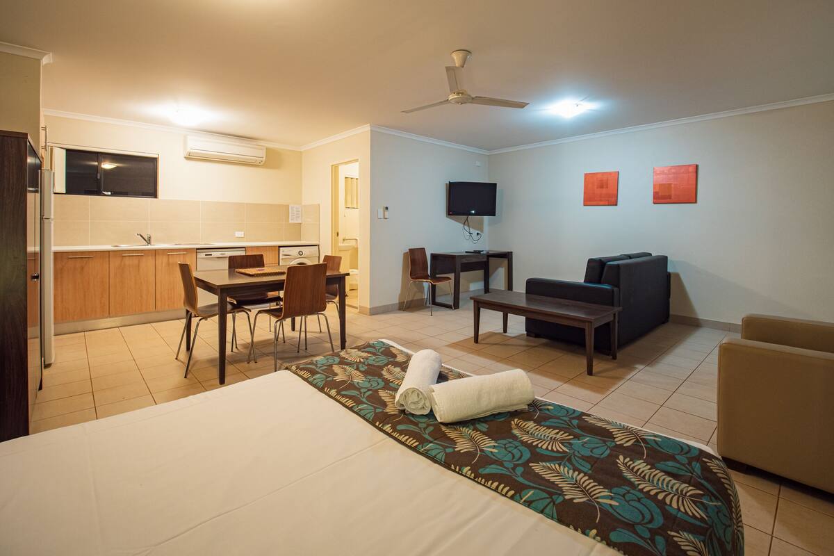 Ein Hotelzimmer mit einem Bett, einem Schreibtisch, einem Sessel, einer Couch, einem Fernseher und einem Deckenventilator.