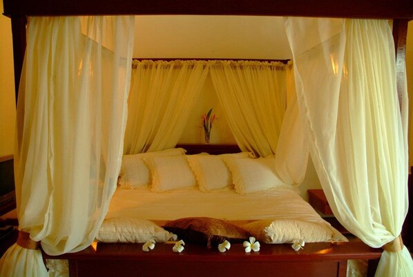 A bed with a canopy, pillows, and a vase with flowers. - Crystal Paradise Resort, Spa & Winery (Narra)