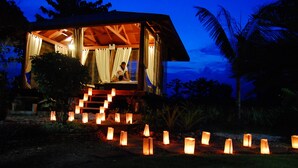 Una cabaña de madera acogedora y bien iluminada, con balcón y rodeada de un jardín con faroles.