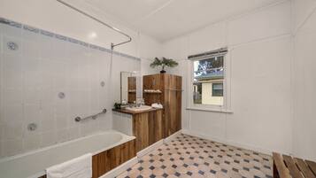 A bathroom with a bathtub, wooden vanity, and a window with a view.