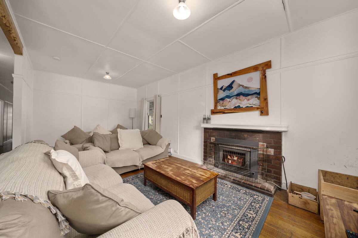 A living room with a sofa set, a fireplace, and a painting on the wall.