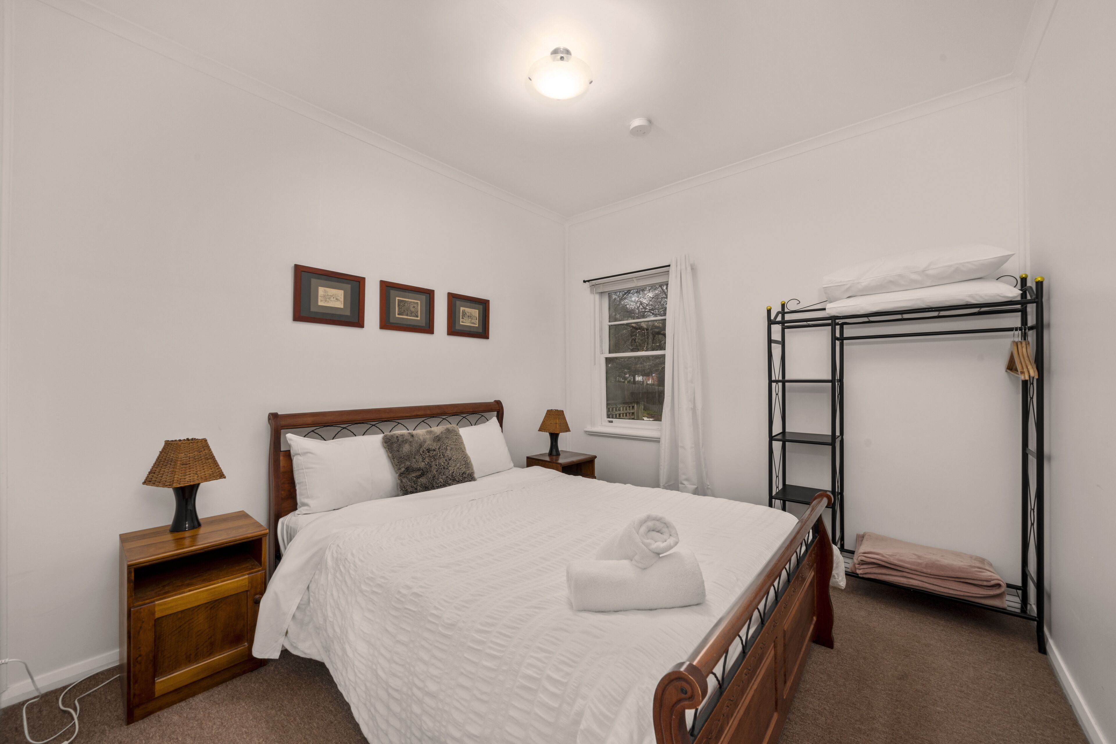 Een keurig opgemaakt slaapkamer met een bed, nachtkastje, lamp en een stapelbed.