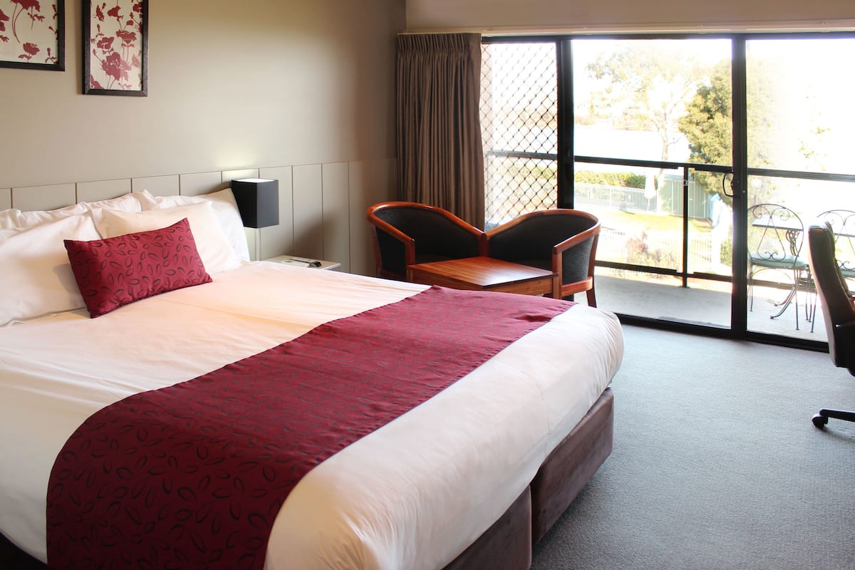 A hotel room with a large bed, a desk, and a chair.