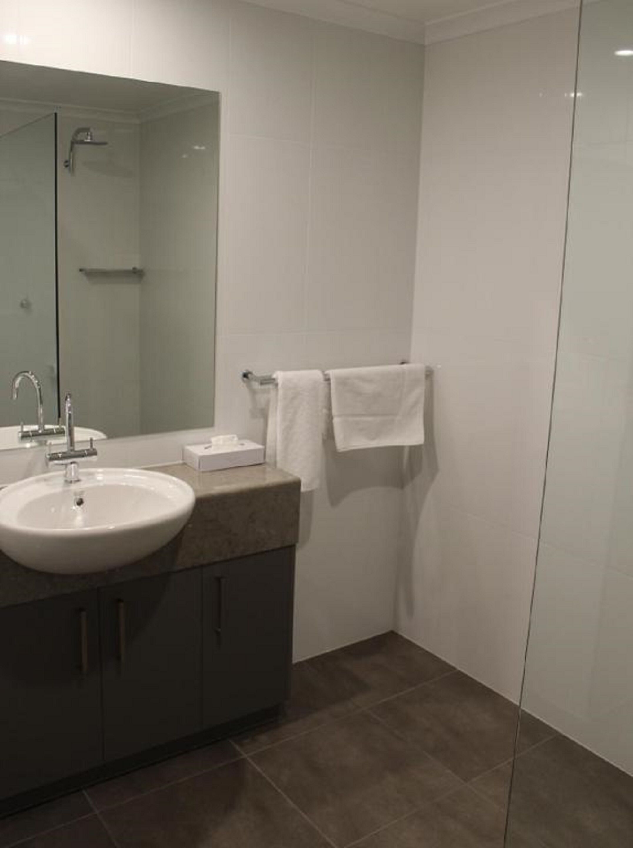 A modern bathroom with a large mirror, a sink, and a towel rack.