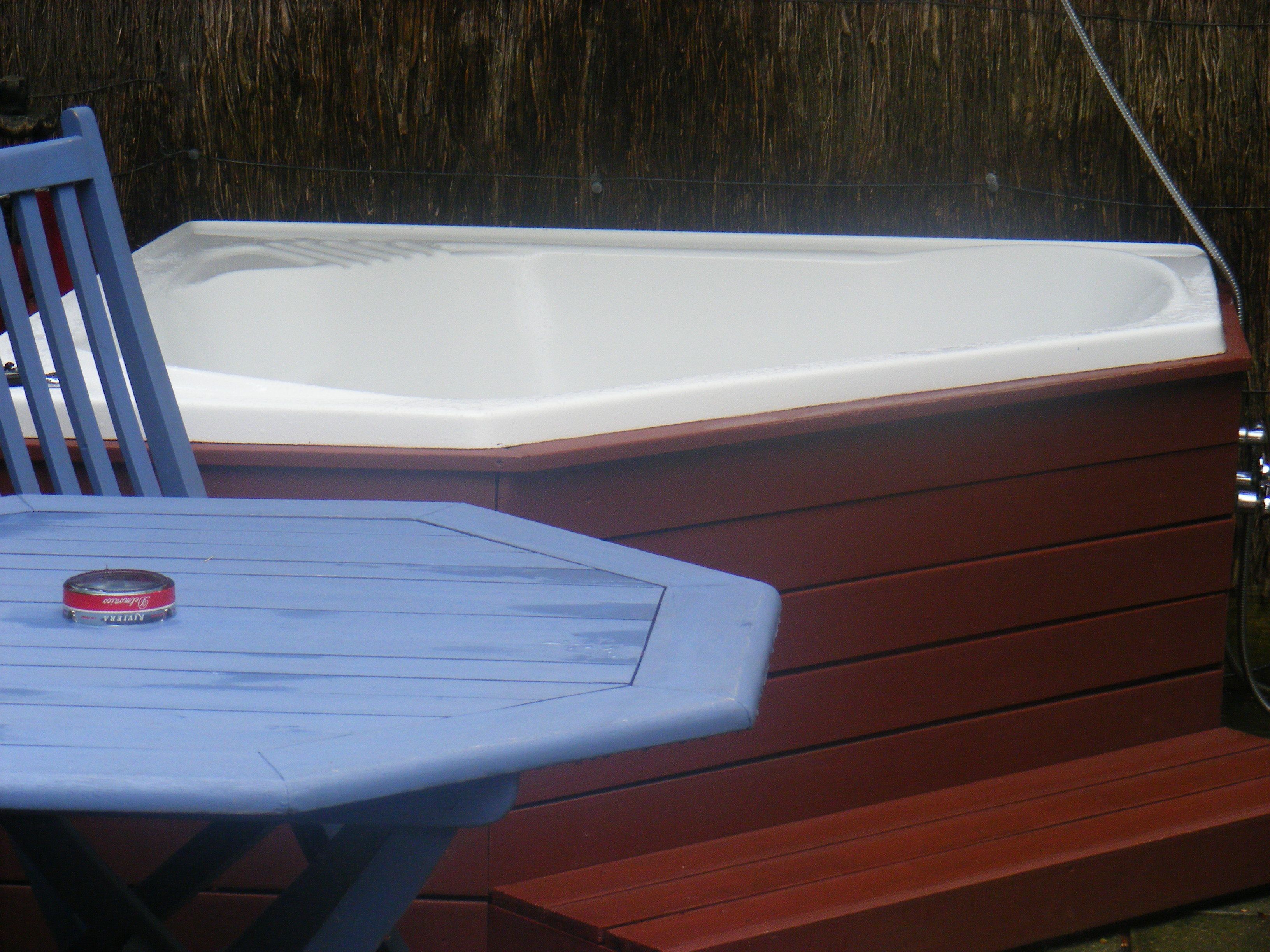 Un bain à remous avec une chaise en bois et une table placée devant.