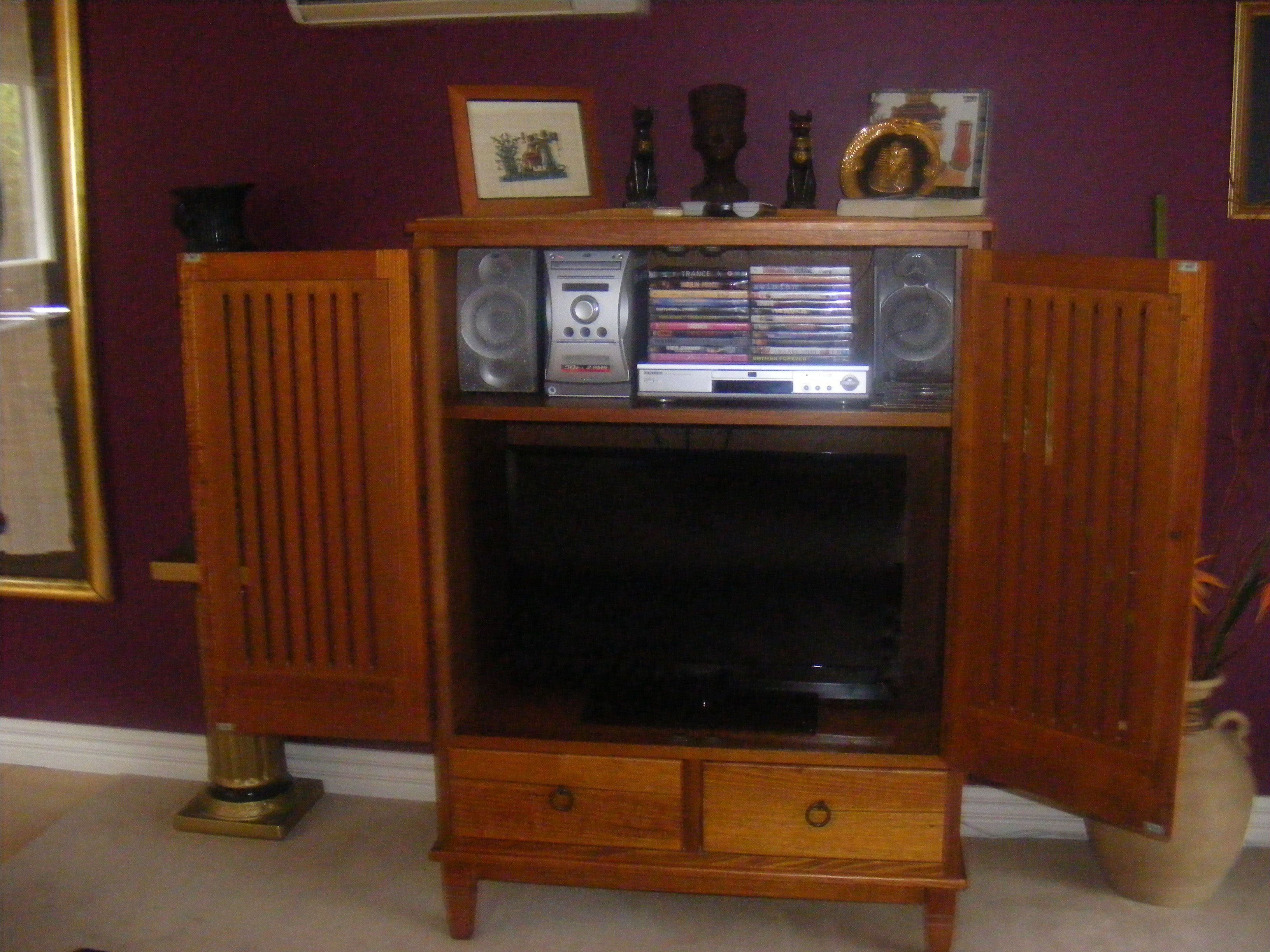 A wooden entertainment center with a television, speakers, and a CD player.