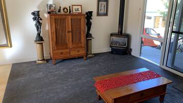 A living room with a wooden cabinet, a red decorative runner on a coffee table, a fireplace, and a large window with a view of the outside.