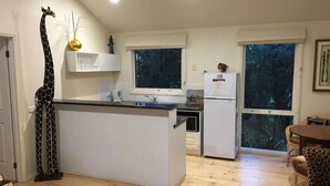 Een moderne keuken met een centraal eiland, witte kasten, een koelkast en een eethoek met tafel en stoelen.