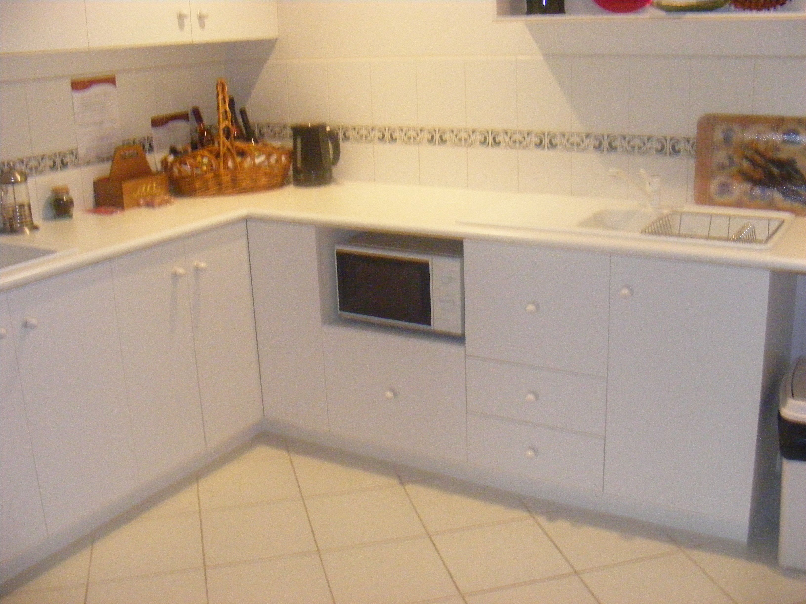 A kitchen with white cabinets, a microwave, and a sink.