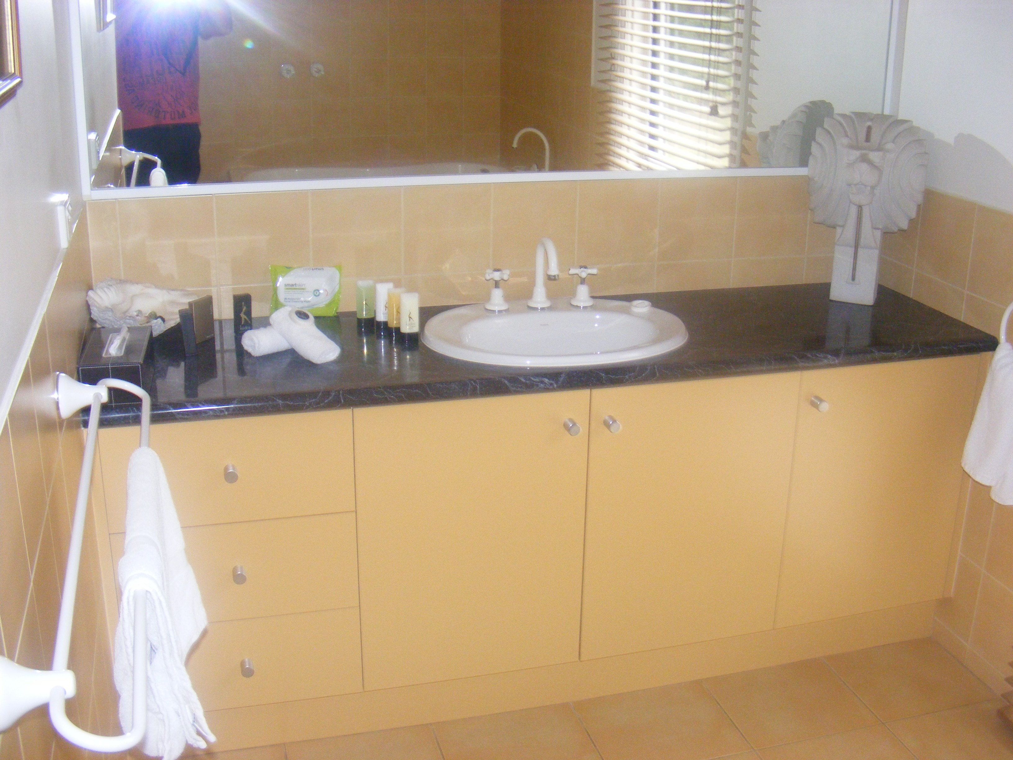 A bathroom with a sink, mirror, towel rack, and toiletries.