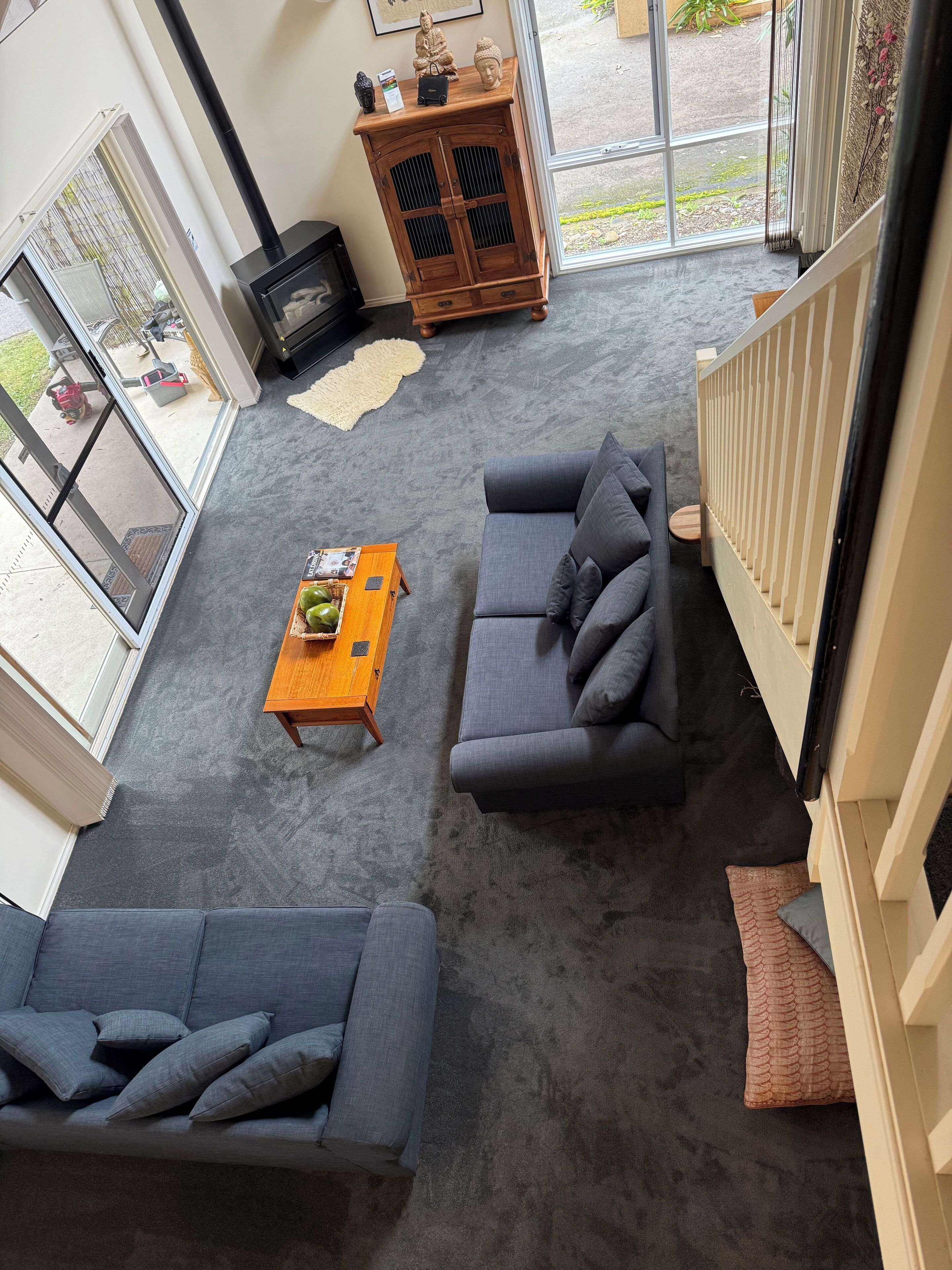 Una sala de estar moderna con alfombra gris, dos sofás grises, una mesa de centro de madera y una chimenea.