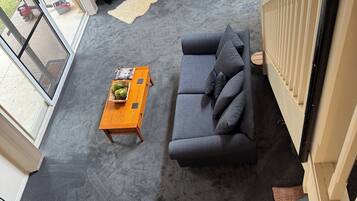 Una sala de estar moderna con alfombra gris, dos sofás grises, una mesa de centro de madera y una chimenea.