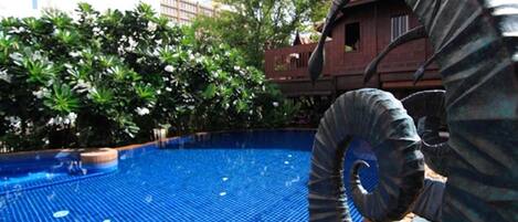 Una piscina con una escultura espiral al frente.