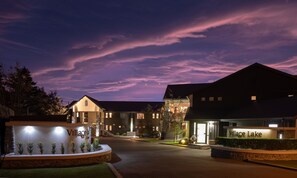 Entrada de un hotel con un letrero que dice "Village Lake" bajo un cielo crepuscular.