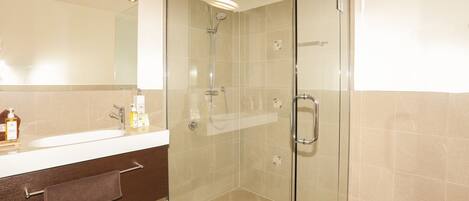 A modern bathroom with a glass-enclosed shower, a vanity with a mirror, and a towel rack.