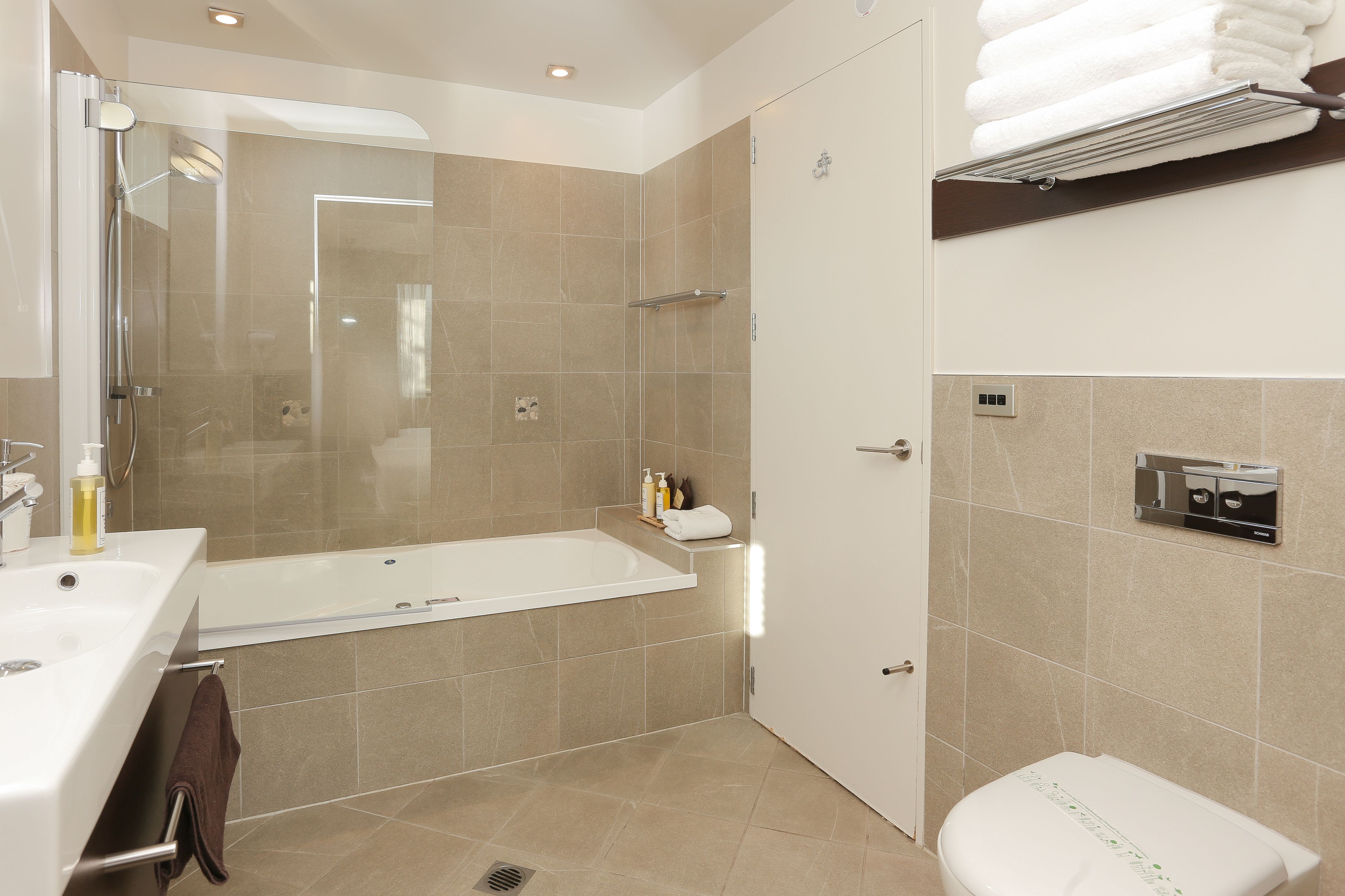 Une salle de bain moderne avec une douche à parois de verre, une baignoire blanche, des toilettes et un lavabo équipé d’un porte-serviettes.