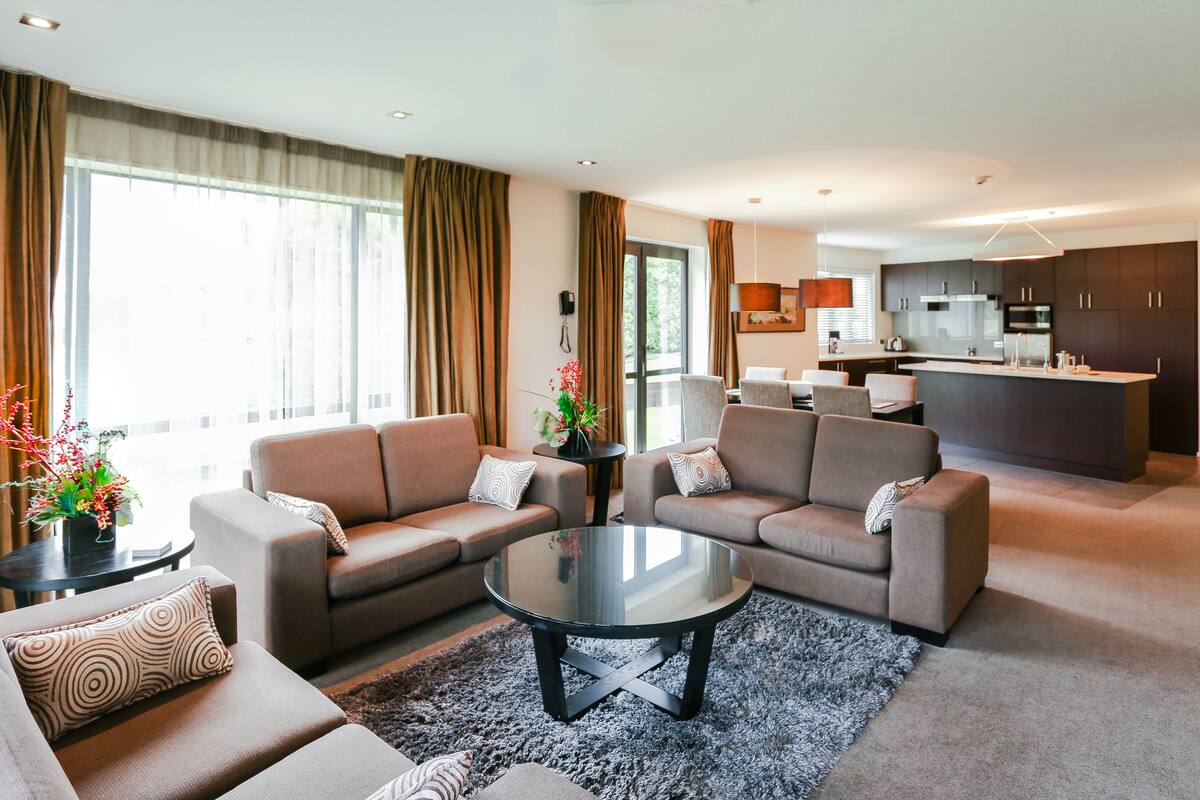 A modern living room with two sofas, a coffee table, and a kitchen in the background.
