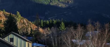 A mountain landscape with snow-covered peaks and a residential area with houses at the base.