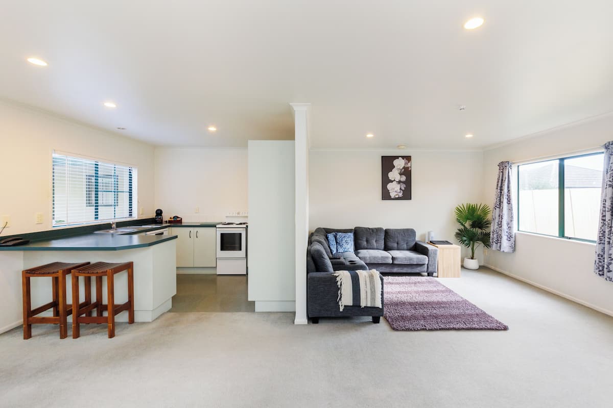 A modern apartment with a kitchen, a living area with a sofa and a coffee table, and a small dining area.