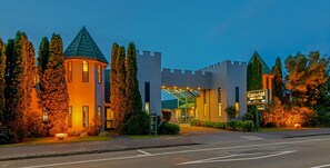 A castle-themed hotel entrance with a glass canopy, ivy-covered towers, and a sign indicating it's a motor lodge.