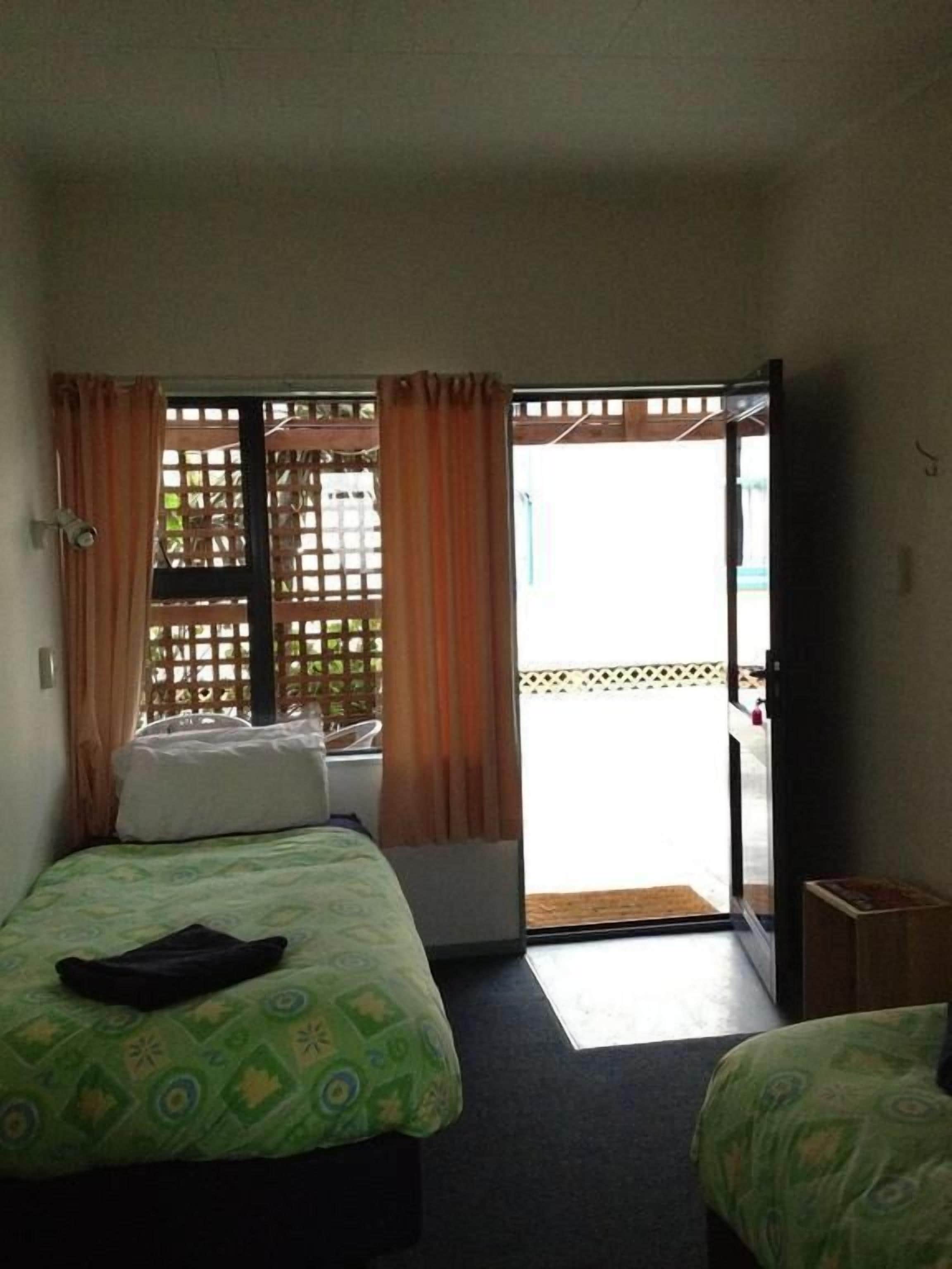Una habitación de hotel con una cama, una mesita pequeña y un balcón al que se accede por una puerta corredera.