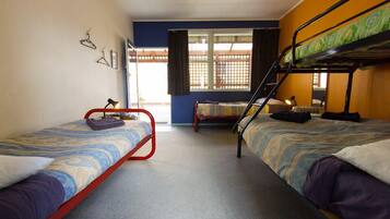 A dormitory room with two single beds, a bunk bed, a window with curtains, and a door.