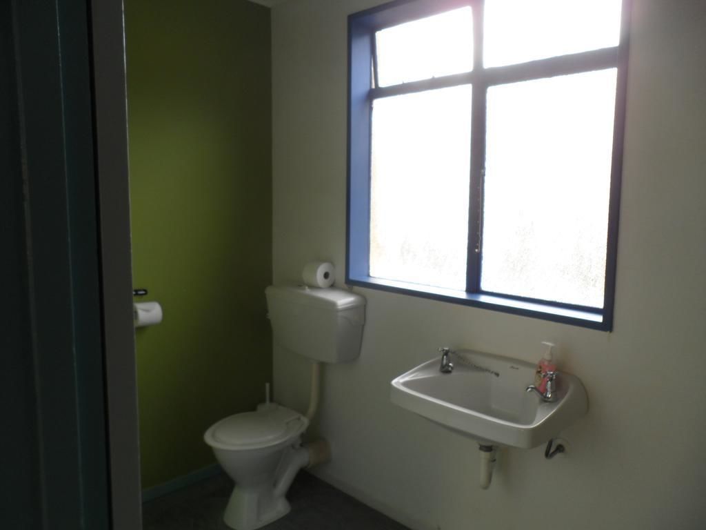 A small bathroom with a toilet, a sink, and a window.