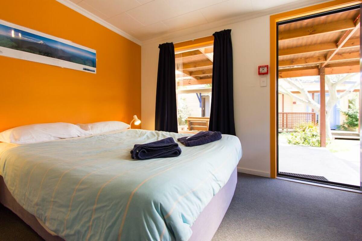 Une chambre d’hôtel avec un lit, une table de chevet, une fenêtre avec des rideaux et une vue sur l’extérieur.