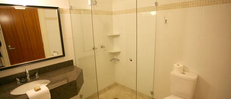 Un baño con cabina de ducha de vidrio, un lavabo con toalla y un inodoro.
