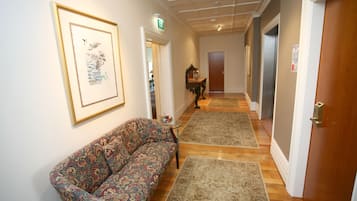 Un couloir avec un canapé à motifs, des tapis et une œuvre d’art encadrée accrochée au mur.