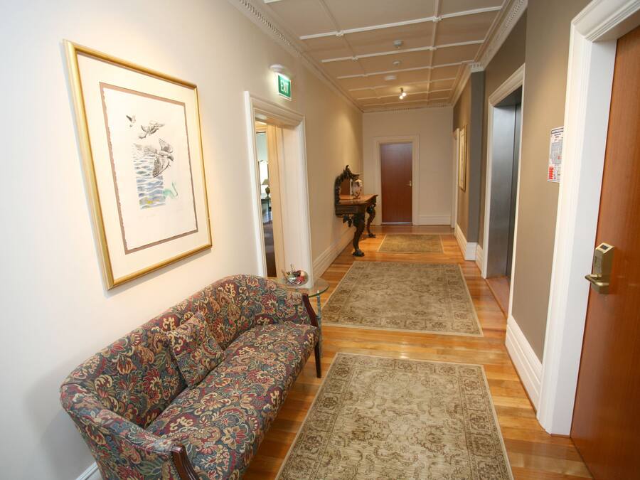 Un couloir avec un canapé à motifs, des tapis et une œuvre d’art encadrée accrochée au mur.