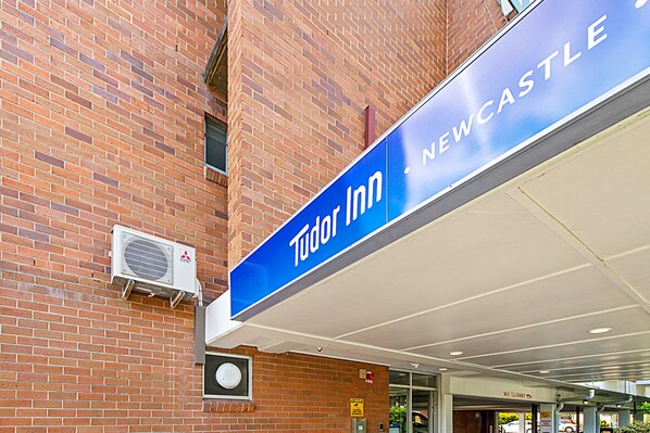 A brick building with a blue sign for 'Tudor Inn Newcastle'.