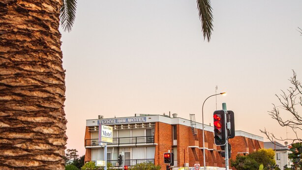 A building with a sign for 'Tudor Inn Motel' and a traffic light.