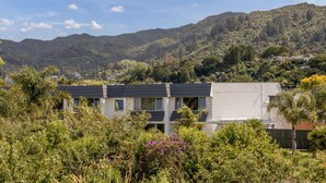 A residential building with multiple units, surrounded by lush greenery and mountains in the background. - Avalon Motel Thames – Wenzel Motels (Thames)