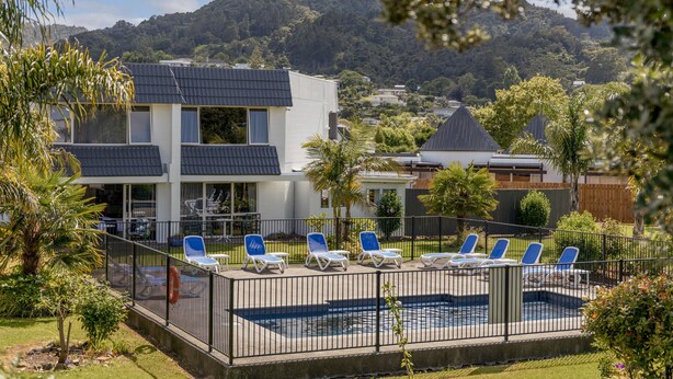 A modern building with a swimming pool and lounge chairs. - Avalon Motel Thames – Wenzel Motels (Thames)