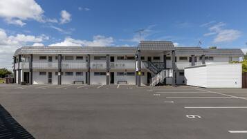 A motel with a parking lot, multiple rooms, and a covered outdoor area.