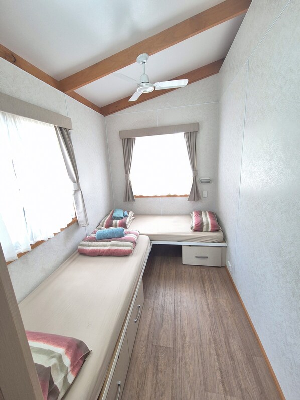 Un dormitorio pequeño con cama, escritorio, ventilador de techo y ventana.