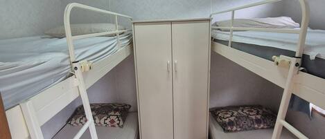 A room with bunk beds, a wardrobe, and a window.