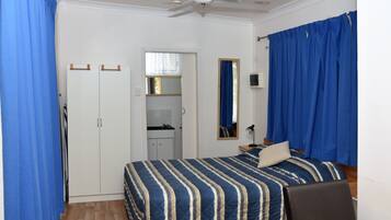A bedroom with a bed, a wardrobe, a ceiling fan, and a bathroom visible through an open door.