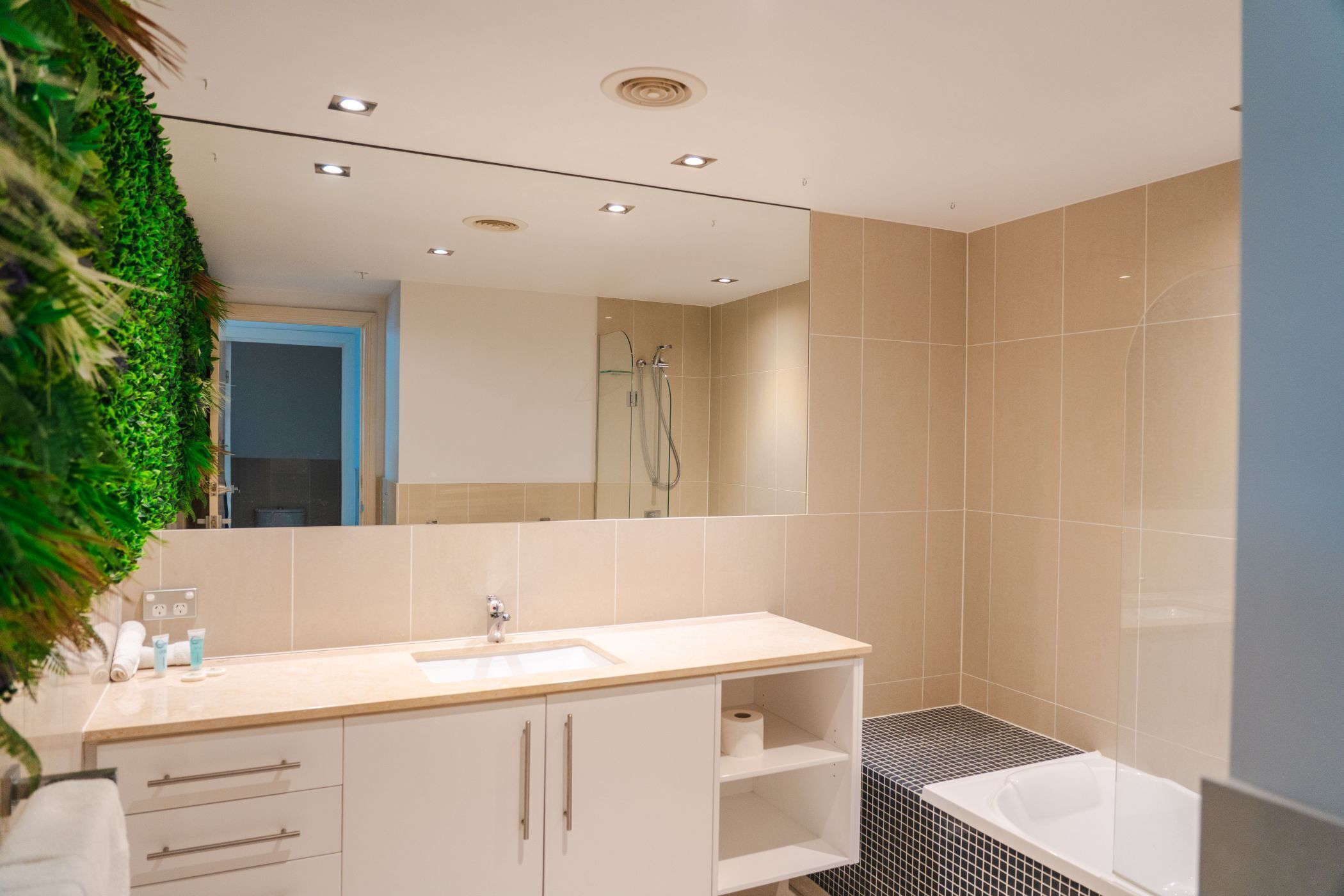A modern bathroom with a large mirror, a sink, a shower, and a bathtub.