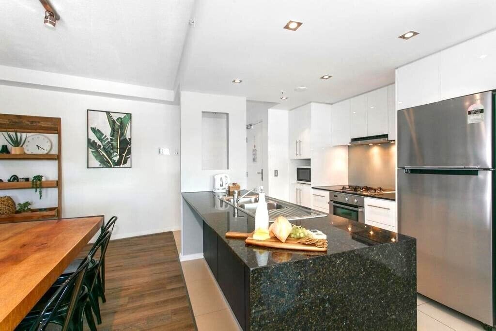 Una cocina moderna con una isla central, electrodomésticos de acero inoxidable y una mesa de comedor de madera.