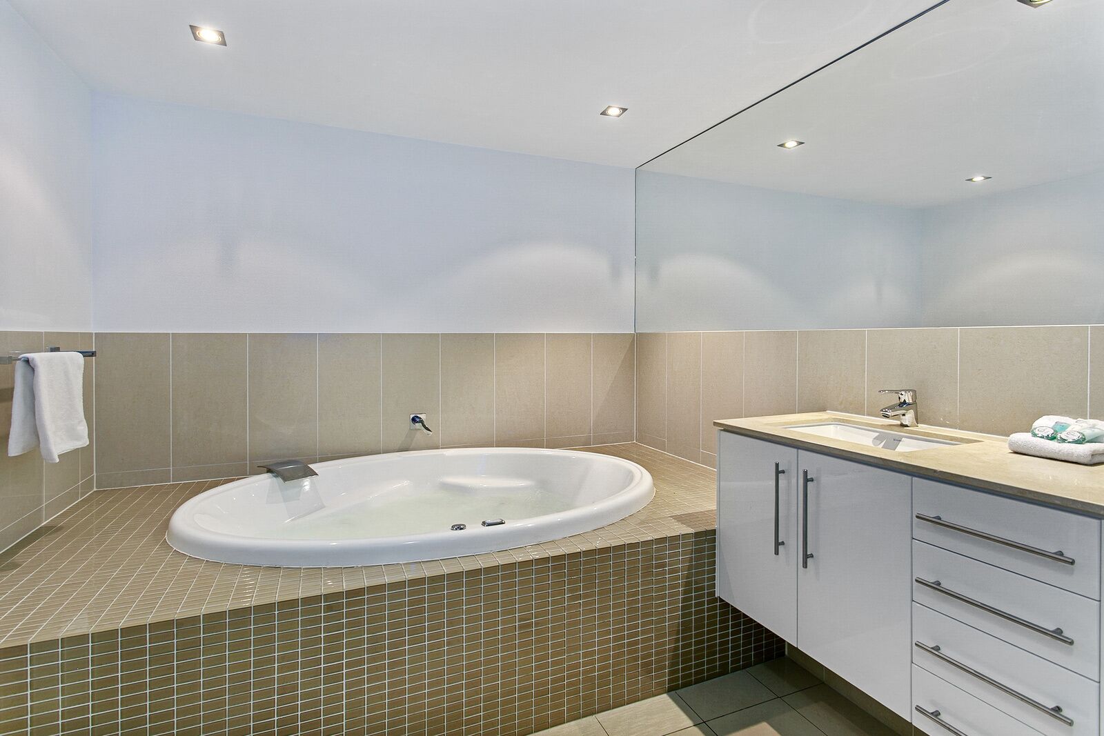 Een moderne badkamer met een vrijstaand bad, een wastafel en een badkamermeubel met lades.