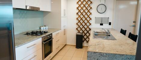 A modern kitchen with white cabinets, a stainless steel range, and a granite countertop.