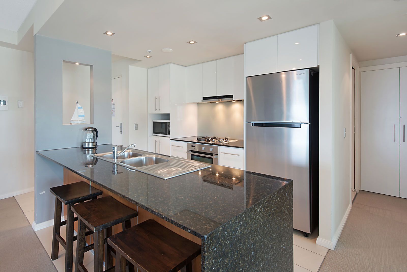 A modern kitchen with a central island, stainless steel appliances, and white cabinetry.