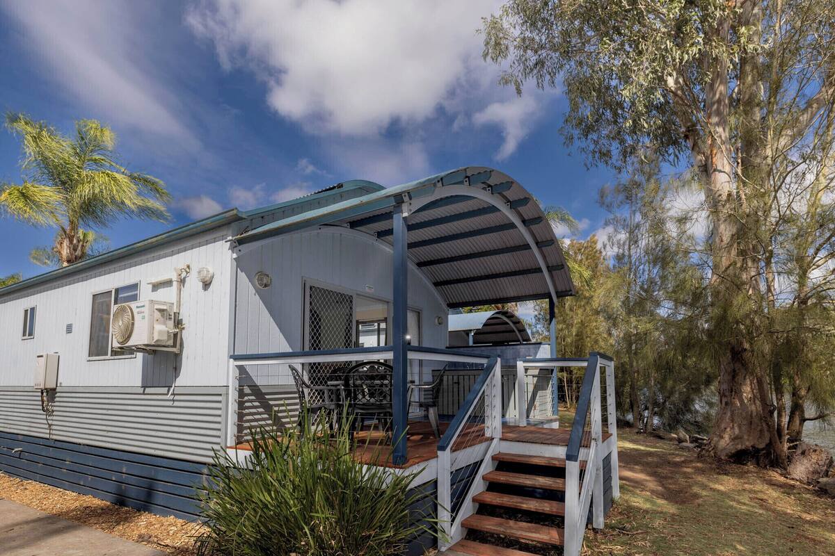 A single-story mobile home with a covered porch and a staircase leading to the entrance.